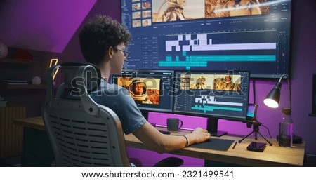 Young editor, video maker edits sound tracks for movie with astronauts, works at home office. Film footage and program interface with tools on computer and big digital screen. Post production concept.