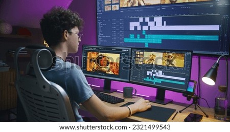 Young editor, video maker edits movie with astronauts, works at home office. Film footage and program interface with tools and sound tracks on computer and big digital screen. Post production concept. Royalty-Free Stock Photo #2321499543