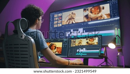 Young editor, video maker edits sound tracks for movie with astronauts, works at home office. Film footage and program interface with tools on computer and big digital screen. Post production concept. Royalty-Free Stock Photo #2321499549