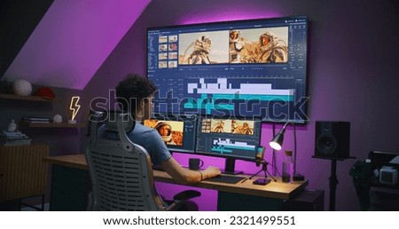 Young editor, video maker edits movie with astronauts, works at home office. Film footage and program interface with tools and sound tracks on computer and big digital screen. Post production concept.