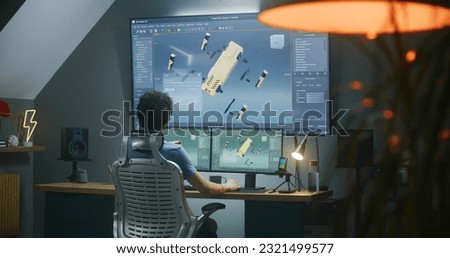 Young 3D designer creates robot 3D visualization and prototype, works on project at home on computer and big digital screen with professional program interface and tools for 3D modeling and design.