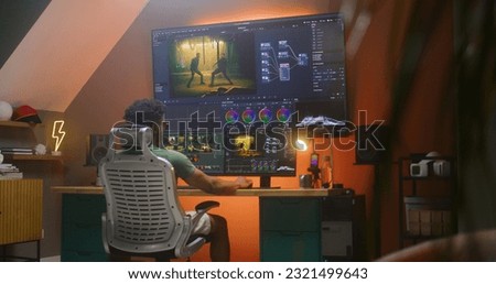 African American colorist edits action movie, makes color correction in professional software on multi-monitor computer and big digital screen, works at home office. Concept of film post production.