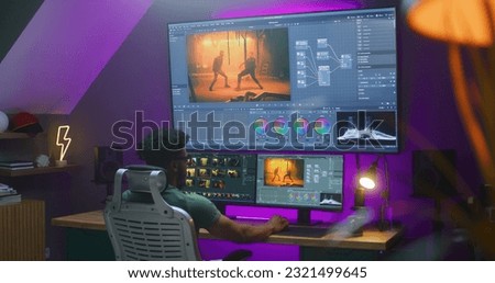 African American video maker edits action movie, makes color grading, works at home. Software interface with RGB tools and wheels on computer and big digital screen. Concept of film post production.
