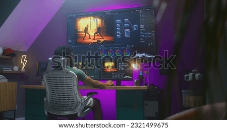 African American colorist edits action movie, makes color correction in professional software on multi-monitor computer and big digital screen, works at home office. Concept of film post production.