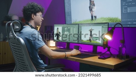 Young 3D designer draws video game character, creates animation. Teenager works remotely at home on computer and big digital screen with professional software interface for 3D modeling and design. Royalty-Free Stock Photo #2321499685