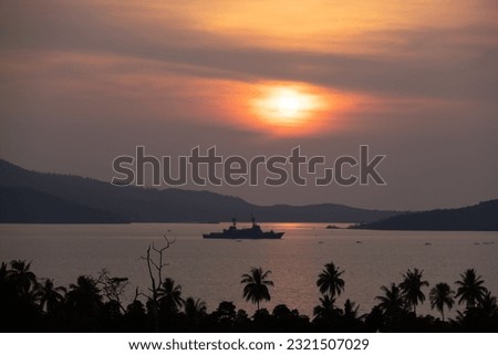 Intense orange and pink sunset above the water in Puerto Princesa, Palawan, Philippines. Sun going down, burning sky, golden hour. Warship in the distance