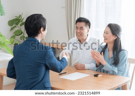 Asian couple shaking hands with businessman Royalty-Free Stock Photo #2321514899