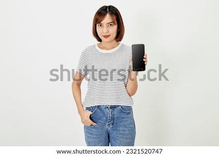 Cute asian short brunette hair woman promotes smartphone app mockup of blank screen, woman blogger showing personal social media page hold phone look camera happily smiling on white background