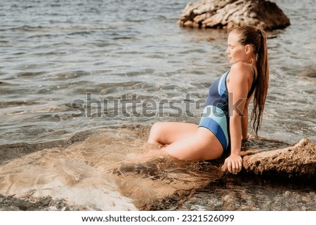 Woman travel sea. Happy tourist in blue swimwear takes a photo outdoors to capture memories. woman traveling and enjoying her surroundings on the beach, with volcanic mountains in the background.