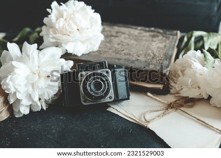 retro photo camera with book and fresh peony flowers.