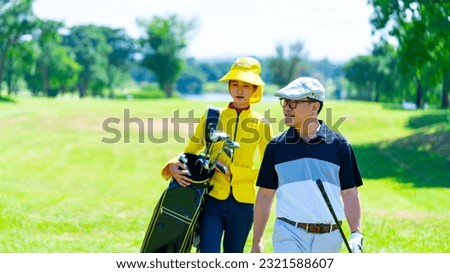 Asian man golfer walking together with female caddy on fairway at country club golf course. Healthy man enjoy outdoor activity lifestyle sport training golfing at golf club on summer holiday vacation. Royalty-Free Stock Photo #2321588607