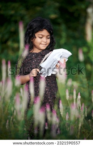 Asian little girl reading a book and playing at wild nature park