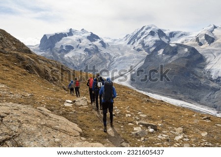 Panorama view with mountain Dufourspitze (left), Gorner Glacier, mountain Lyskamm (right) and group of mountaineers hiking towards mountain massif Monte Rosa in Pennine Alps, Switzerland Royalty-Free Stock Photo #2321605437