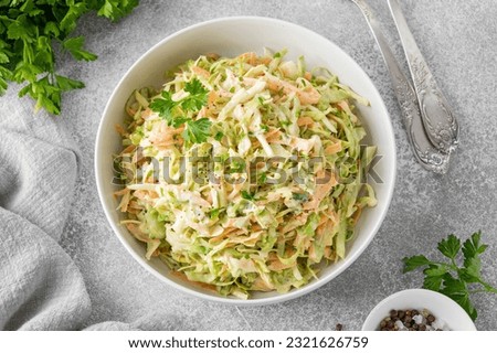 Traditional cole slaw salad in a bowl on a gray concrete background. Salad with cabbage, carrot and mayonnaise sauce. Selective focus, copy space Royalty-Free Stock Photo #2321626759