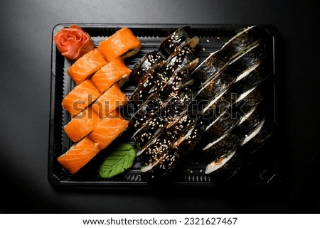 Sushi rolls set maki and Philadelphia served on black tray on dark background. Top view