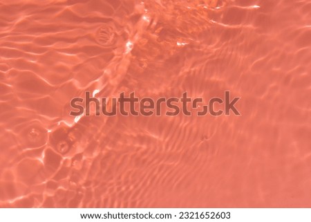 Orange water with ripples on the surface. Defocus blurred transparent yellow colored clear calm water surface texture with splashes and bubbles. Water waves with shining pattern texture background.