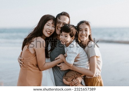 Asian Family Hugging and Walking Along the Beach with Father, Mother, Teenage Girl, Boy, during Sunset on the Shore with Ocean Background and Sunlight