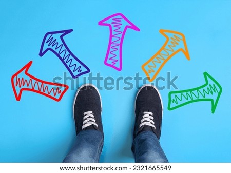 Choosing future profession. Teenager standing in front of drawn signs on light blue background, top view. Arrows pointing in different directions symbolizing diversity of opportunities Royalty-Free Stock Photo #2321665549