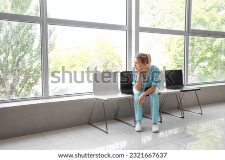 Sad female medical intern sitting in clinic