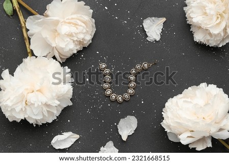 Composition with stylish female bracelet and beautiful peony flowers on dark background