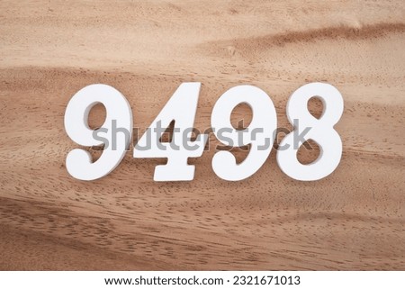 White number 9498 on a brown and light brown wooden background.