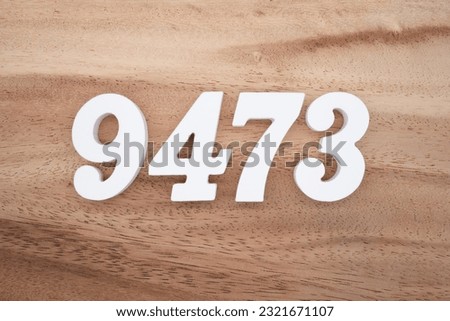 White number 9473 on a brown and light brown wooden background.