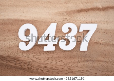 White number 9437 on a brown and light brown wooden background.
