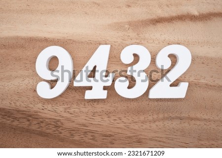 White number 9432 on a brown and light brown wooden background.