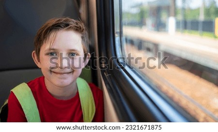 smiling boy 10 years old sitting by the window in commuter electric train in summer Royalty-Free Stock Photo #2321671875