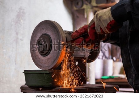 Professional Fitter Man Using Metal Polishing Machine for Metal Rods Sharpening With Sparks in Workshop. Horizontal Image