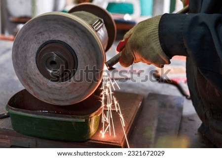 Hands of Professional Fitter Man Using Metal Polishing Machine for Metal Rods Sharpening With Sparks in Workshop. Horizontal Image Orientation