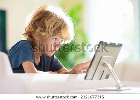 Kids with tablet computer. Child with pc watching movie or playing game. Educational online program for school child. Boy with digital device and gadget. Screen time and education for young kid.  Royalty-Free Stock Photo #2321677315