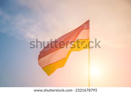 Flag of Uzbekistan waving on a sunset or sunrise dramatic cloudy sky background.