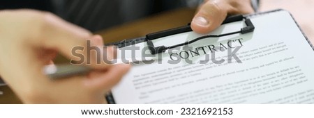 Manager holding out document contract on clipboard and pen for signing closeup