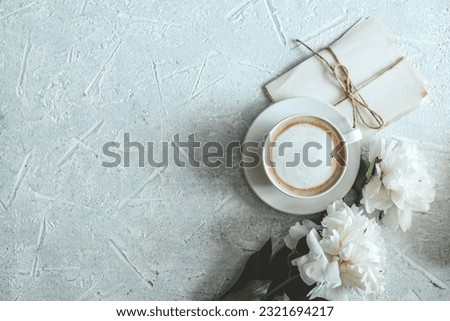 Summer composition top view. Cup of coffee, peonies and vintage letters on gray background.