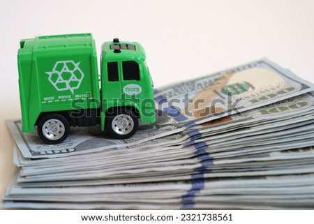 Savings at recycling. Garbage truck on a pile of dollars. Royalty-Free Stock Photo #2321738561