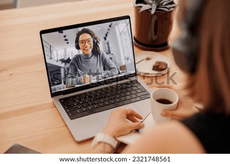 Close up of woman talking via video call with friends while sitting in coworking during working day