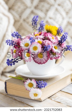 Countryside decor, old book, wooden background, straw hat. Greeting postcard with bright summer or spring flowers in a cute cup. Congratulations for Mother's or Women's day, birthday or anniversary