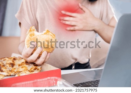 woman suffering from acid reflux , heartburn after over eating junk food, pizza and burger  Royalty-Free Stock Photo #2321757975