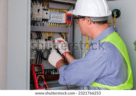 Electrician engineer tests electrical installations and wires on relay protection system. Bay control unit. Medium voltage switchgear. Royalty-Free Stock Photo #2321766253