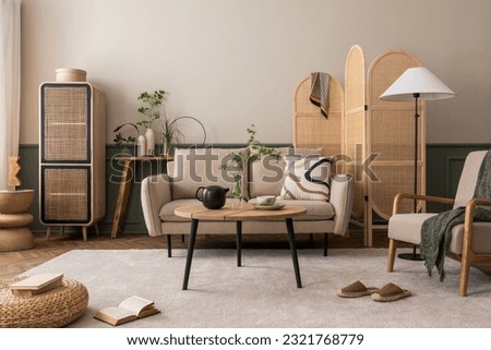 Creative composition of living room interior with beige sofa, wooden coffee table, rattan sideboard, partition wall, lamp,  carpet, stylish armchair and personal accessories. Home decor. Template Royalty-Free Stock Photo #2321768779