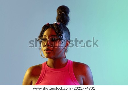Calm, composed. Picture of young beautiful African girl, female model looking away isolated on blue green background in neon light. Concept of human emotion, facial expression. Copy space for ad.