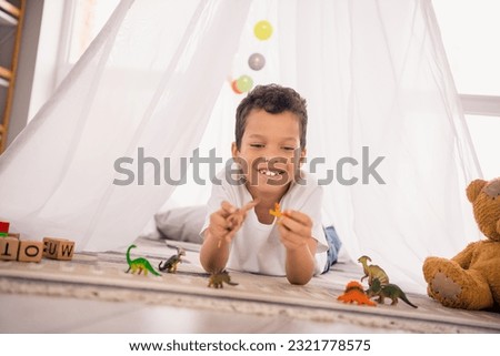 Photo of cute adorable preschool boy in homemade camp playing with animal toys dinosaurs learn about jurassic history in house