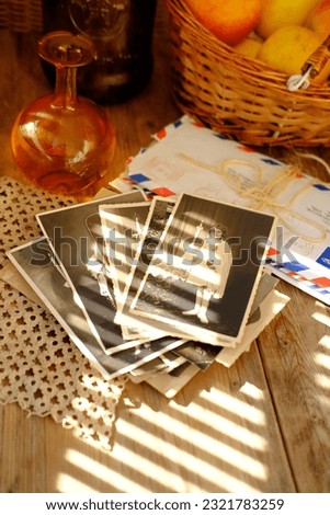 old vintage monochrome photographs scattered on rustic wooden table, Autumn composition with basket of apple, bottle of apple cider, hard light, concept family tree, genealogy, cozy autumn mood