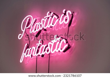 A vibrant neon sign featuring the text Plastic is fantastic illuminated in a soft pink light