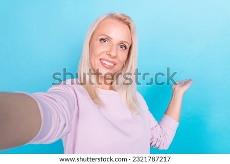 Selfie portrait of cheerful mature woman wearing light pink blouse video call online blog show mockup isolated on blue background.
