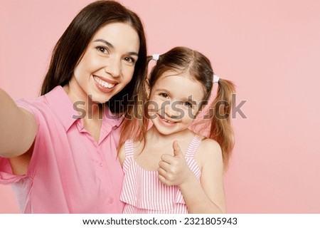 Close up happy woman wear casual clothes with child kid girl 6-7 years old. Mother daughter do selfie shot pov on mobile cell phone isolated on plain pastel pink background. Family parent day concept
