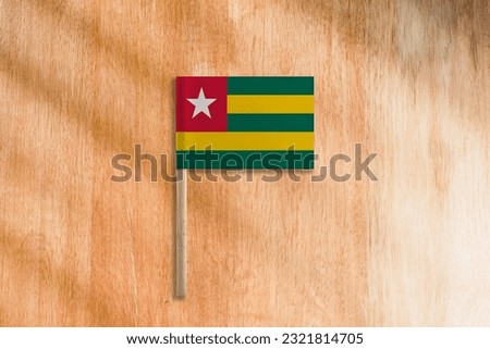The Flag of Togo with Pole on Wooden Background.