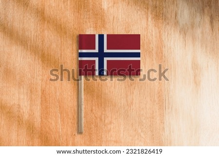 The Flag of Norway with Pole on Wooden Background.