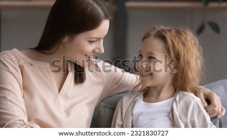 Pleasant conversation. Happy preteen girl sit on couch glad to talk to friendly female teacher psychologist answer questions discuss school life. Smiling little daughter ask supportive mom for advice Royalty-Free Stock Photo #2321830727